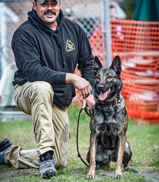 Jeremy Cormier, founder of V3 Canine Academy, kneeling beside his dog
